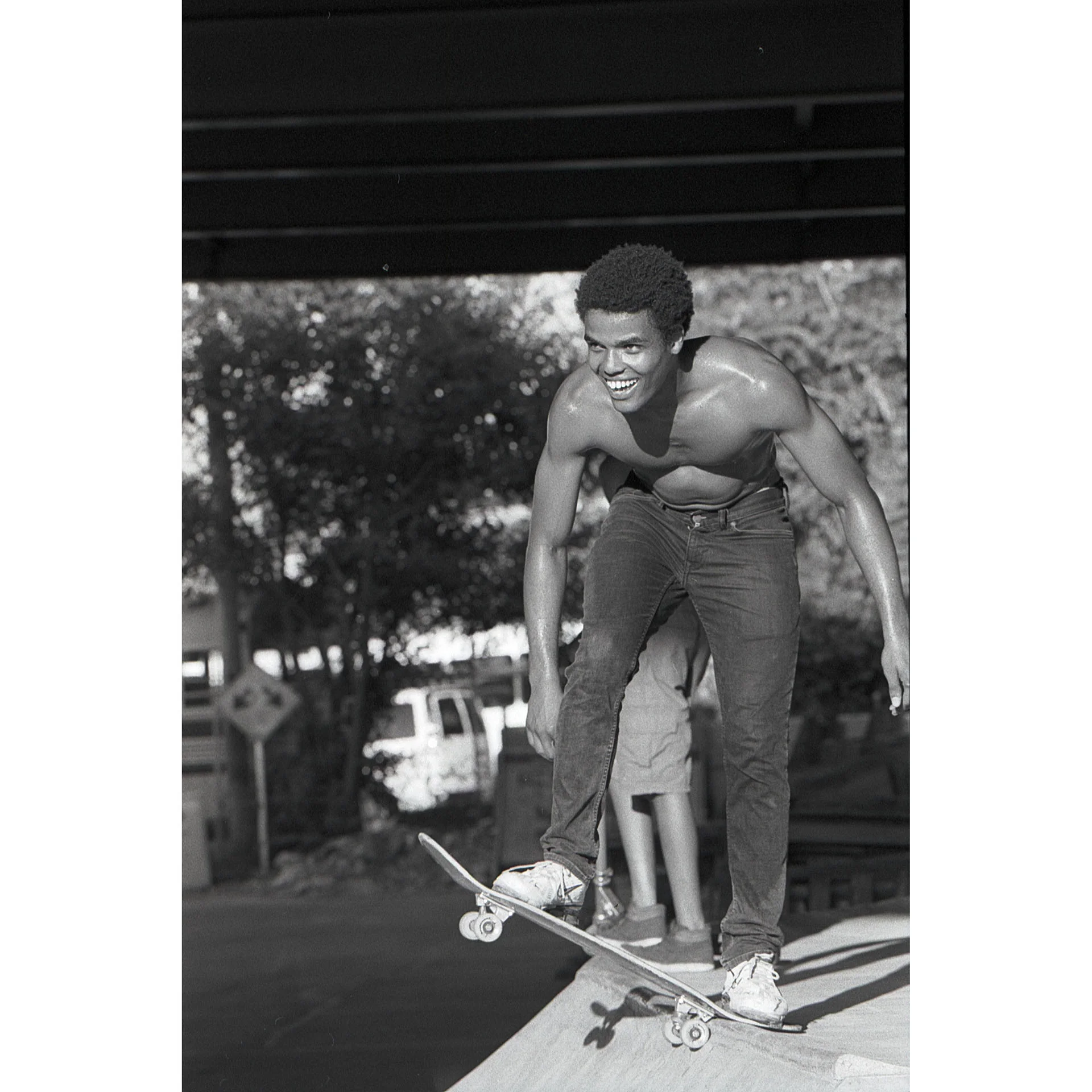 Shirtless boy smiling while getting ready to drop in on an obstacle. Photo by Dylan Shanahan.